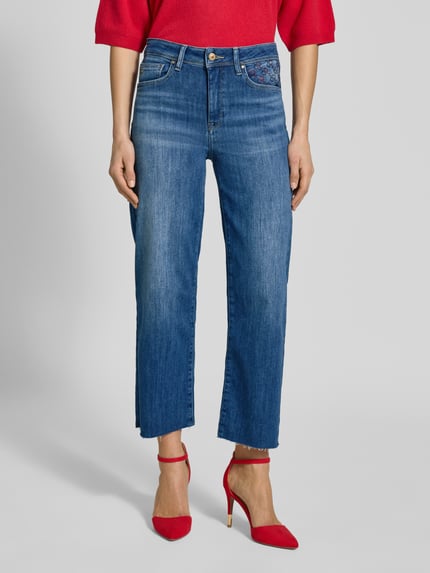 Vrouwenmodel draagt Jeans in verkorte pasvorm Modell 'KIRA 6/8' van Raffaello Rossi, katoenmix met stretch, siersteentjes, franjes, vooraanzicht, detail uit context: taillewijdte 39 cm, binnenbeenlengte 65 cm bij maat 36.