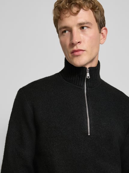 Männermodel trägt Relaxed Fit Strickpullover aus elastischem Woll-Mix von JACK & JONES, schwarze Struktur, Nahaufnahme Oberkörper.