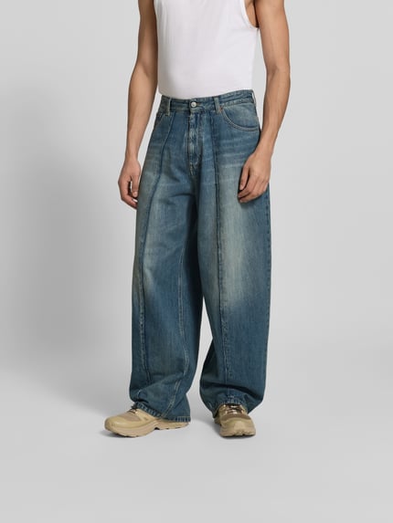 Męskid model nosi Wide Fit Jeans im 5-Pocket-Design od MM6 Maison Margiela, bawełna, krój wide fit, 5 kieszeni, ozdobne szwy, zapięcie na guzik i zamek błyskawiczny, denim w odcieniach niebieskiego, widoczne przetarcia, prosty krój, Ganzkörperansicht von vorne.