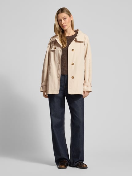Frauenmodel trägt beigen Trenchcoat mit Stehkragen und Ärmelriegeln von Fuchs Schmitt, Regular Fit, Ganzkörperansicht von vorne.