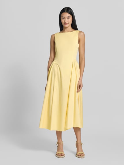 Frauenmodel trägt Midikleid mit Rundhalsausschnitt Modell 'NICOLE' von MANGO aus Baumwoll-Elasthan-Mix in zartem Gelb, tailliert, Ganzkörperansicht von vorne.