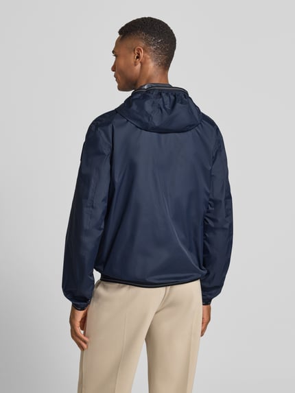 Männermodel trägt Jacke mit Label-Patches Modell 'Dodge' von Blauer Usa in Dunkelblau mit Kapuze, Gerader-Schnitt, Rückenlänge 69 cm, Ganzkörperansicht Rückansicht.