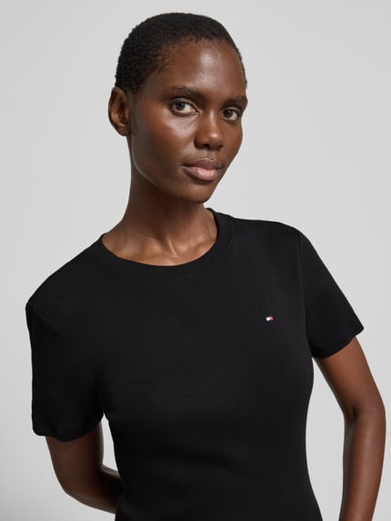 Frauenmodel trägt Slim Fit T-Shirt aus reiner Baumwolle von Tommy Hilfiger, Optik: Unifarben, Logo-Stitching, Rundhals, Kurzarm, Jersey, Nahaufnahme Oberkörper.