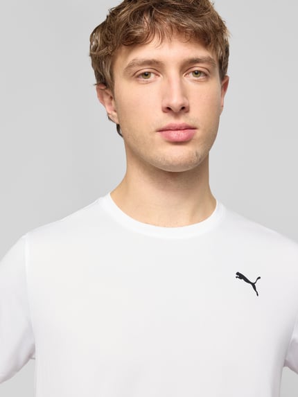 Männermodel trägt T-Shirt mit Logo und Rundhalsausschnitt von PUMA PERFORMANCE in Weiß, Regular Fit, Nahaufnahme Oberkörper.
