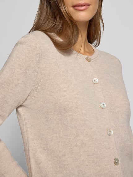 Frauenmodel trägt Cardigan aus Wolle mit Rundhalsausschnitt von Christian Berg Woman in Beige, feine Textur, Nahaufnahme Oberkörper. Reine Wolle, Regular Fit, Knopfleiste, Rückenlänge 58 cm, Ärmellänge 63 cm.