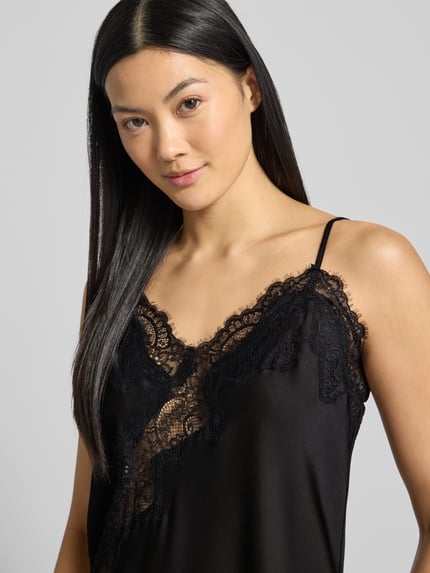 Frauenmodel trägt Kleid aus Satin mit Spitze Modell 'Sorelle' von Neo Noir, schwarze Farbe, Spitzendetail, Spaghettiträger, Nahaufnahme Oberkörper.