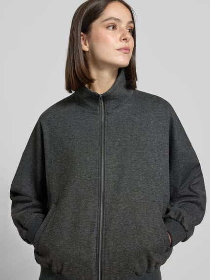 Frauenmodel trägt Jacke aus Viskose-Mix Modell 'EYAM' von DRYKORN in Dunkelgrau mit Stehkragen und Reißverschluss, Nahaufnahme Oberkörper.