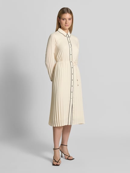 Vrouwenmodel draagt Regular Fit midi-jurk in plooien-look van comma, platte kraag, getailleerde pasvorm, met lange mouwen, afneembare tailleband, doorlopende knoopsluiting, ruglengte maat 36: 120 cm, borstwijdte maat 36: 50 cm, mouwlengte maat 36: 64 cm, crèmekleur, gladde en geplisseerde texturen, plooien, enkellange jurk, geheel lichaamsaanzicht van voren.