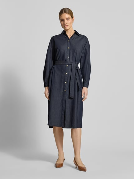 Vrouwenmodel draagt 'Hemdblusenkleid in Denim-Optik mit Bindegürtel' van ARMANI EXCHANGE, puur katoen, recht model, midi-jurk, denimlook, strikceintuur, ruglengte maat 36: 118 cm, borstwijdte maat 36: 62 cm, mouwlengte maat 36: 60 cm, donkerblauw met knopen, gladde textuur, geheel body van voren.