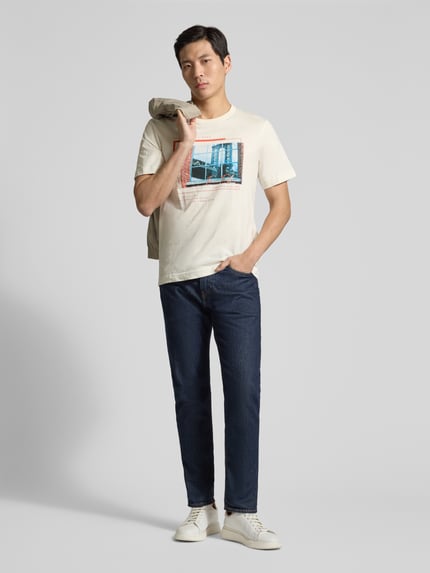 Męski model nosi Regular Fit T-Shirt aus reiner Baumwolle od Tom Tailor, jednokolorowa bawełna, nadruk foto, dekolt okrągły, krótki rękaw, przód cała sylwetka