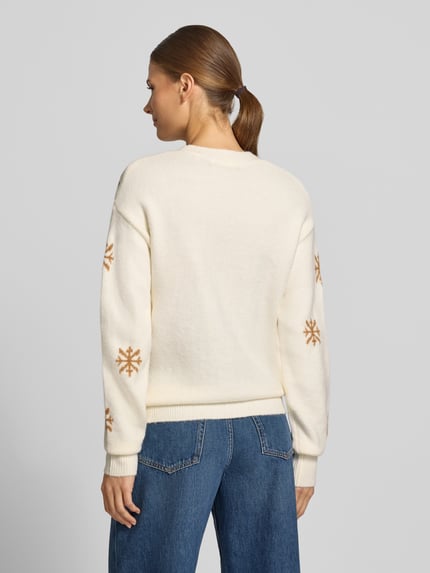 Frauenmodel trägt Strickpullover mit Motiv und Rundhalsausschnitt von Christian Berg Woman, creme mit braunen Akzenten, Material-Mix, Regular Fit, Bommeln, entspannte Kombi mit Jeans, Rückenlänge 57 cm, Ärmellänge 50 cm, Ganzkörperansicht Rückansicht.