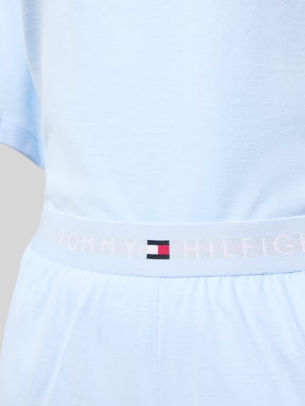 Frauenmodel trägt Regular Fit Pyjama aus reiner Baumwolle von TOMMY HILFIGER in Hellblau mit elastischem Logo-Bund, Nahaufnahme Oberkörper.