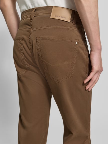 Männermodel trägt Regular Fit Hose mit Eingrifftaschen Modell 'Lyon' von Pierre Cardin, Baumwoll-Elasthan-Mix, Nahaufnahme Rückansicht. Bundweite 41 cm, Innenbeinlänge 80 cm, Farbe Braun, markantes Label, grobe Textur.