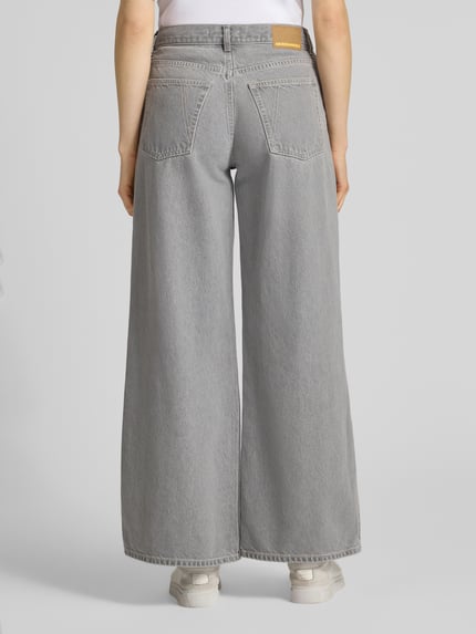 Frauenmodel trägt Wide Leg Jeans aus Lyocell-Baumwoll-Mix Modell 'ASTRAEAAS' von Armedangels in grauer Denim-Optik, 5-Pocket, Ganzkörperansicht Rückansicht.