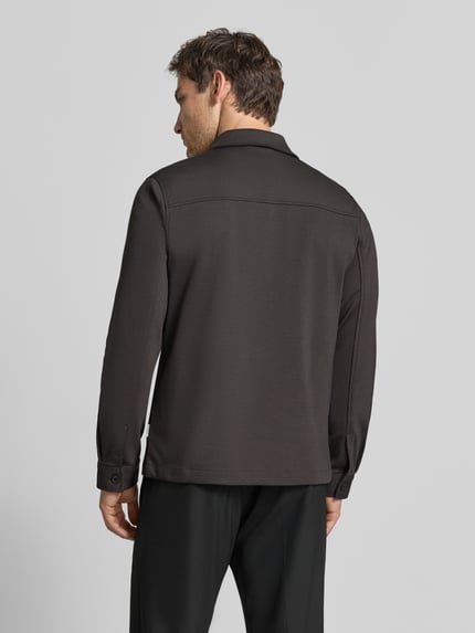 Männermodel trägt Slim Fit Hemdjacke mit Viskose-Anteil von Lindbergh in dunklem Farbton, strukturierte Oberfläche, Ganzkörperansicht Rückansicht. Herren Hemdjacke mit Umlegekragen, Knopfleiste, Brusttasche und Eingrifftaschen, elastischer Material-Mix, Rückenlänge bei Größe M 70 cm.