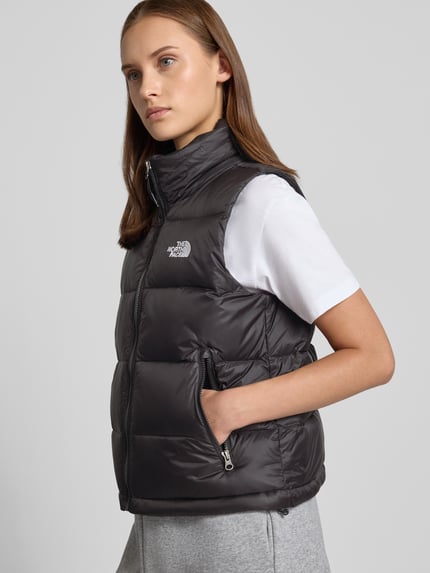 Frauenmodel trägt Steppweste mit Label-Stitching Modell 'HYDRENALITE DOWN A-LINE' von The North Face in Dunkelgrau mit Reißverschlusstaschen, Regular Fit, Stehkragen, Ganzkörperansicht von vorne. Rückenlänge, Schulterbreite und Brustweite bei Größe S laut Beschreibung.