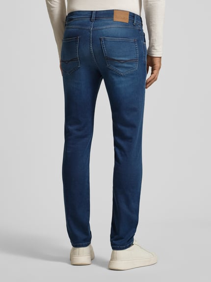 Męski model nosi Slim Fit Jeans mit 5-Pocket-Design von Christian Berg Men, niebieski denim, bio-bawełna ze stretchem, widok całej sylwetki od tyłu.