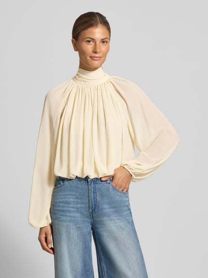 Frauenmodel trägt Regular Fit Bluse mit rückseitiger Schnürung Modell 'NUBE' von MANGO in Creme mit Strukturmuster, Ganzkörperansicht von vorne.