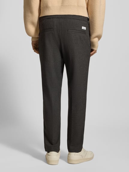 Männermodel trägt Tapered Bundfaltenhose mit Viskose-Anteil von Marc O'Polo Denim in Melange-Optik, seitliche Eingrifftaschen, Ganzkörperansicht Rückansicht.