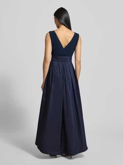 Frauenmodel trägt Abendkleid mit Bindegürtel und rückseitigem Reißverschluss von Christian Berg Cocktail, Material-Mix, A-Linie, Midikleid, Rundhalsausschnitt, Stretch-Anteil, Farbton Dunkelblau, glatte Textur, Ganzkörperansicht Rückansicht.