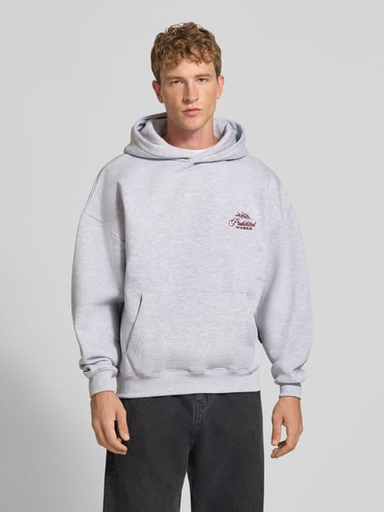 Männermodel trägt Relaxed Fit Hoodie aus Baumwoll-Mix mit Label-Stitching von PROHIBITED, hellgrau, Känguru-Tasche, Ganzkörperansicht von vorne.