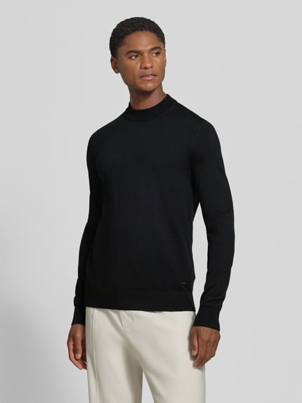 Männermodel trägt Regular Fit Pullover aus reiner Schurwolle Modell 'Davide' von JOOP! COLLECTION in Schwarz, Ganzkörperansicht von vorne.