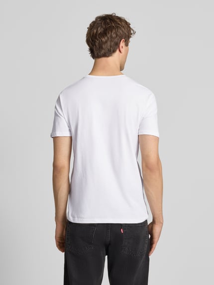 Männermodel trägt T-Shirt aus Baumwolle von Alpha Industries in Weiß, Gerader-Schnitt, Label-Print-Details, Rückenlänge 68 cm, Ganzkörperansicht Rückansicht.