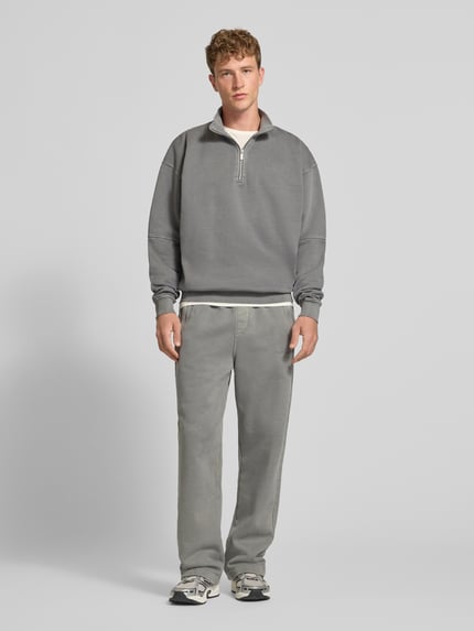 Männermodel trägt Loose Fit Sweatpants aus Baumwoll-Mix mit Label-Detail von PEGADOR, grauer Farbton, elastischer Bund, Eingrifftaschen, Ganzkörperansicht von vorne.