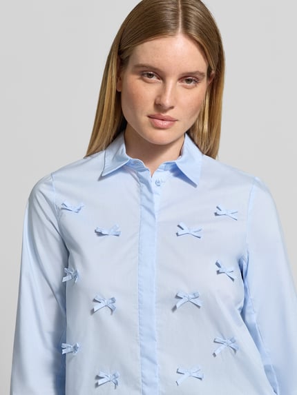 Frauenmodel trägt Regular Fit Hemdbluse aus reiner Baumwolle von Christian Berg Woman, hellblau mit Zier-Applikationen, Nahaufnahme Oberkörper.