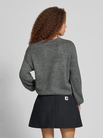 Frauenmodel trägt Pullover mit Schleifen-Schnürung von ONLY in melierter Strickoptik, Struktur, langarm, Loose Fit, Rückansicht.