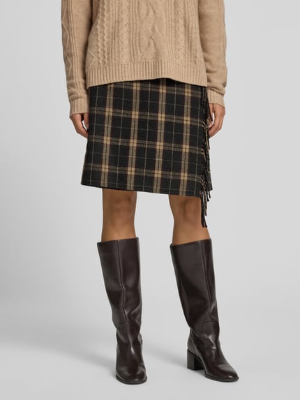 Frauenmodel trägt Knielanger Rock mit Woll-Anteil von Christian Berg Woman mit kariertem Muster in Beige und Schwarz, Fransen-Optik, Material-Mix; Produktdetails: leichte A-Linie, Bundweite 38 cm, Gesamtlänge 52 cm, Ganzkörperansicht von vorne.