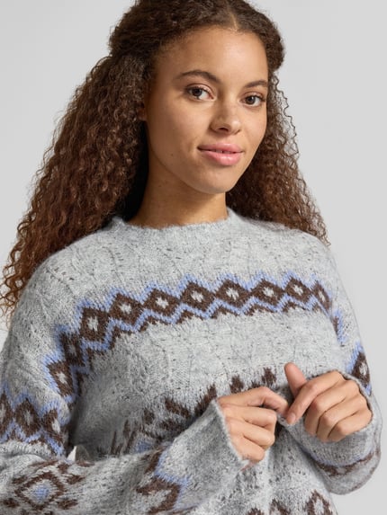 Frauenmodel trägt Pullover mit Effektgarn-Details Modell 'ONLSTOCKHOLM' von ONLY in Strickoptik, geometrisches Muster, Nahaufnahme Oberkörper.