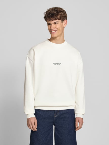 Männermodel trägt Oversized Sweatshirt mit Logo-Print Modell 'Stavoren' von Pegador, weiß, Baumwoll-Mix, Rundhalsausschnitt, elastische Abschlüsse, Oversized-Fit, Ganzkörperansicht von vorne.