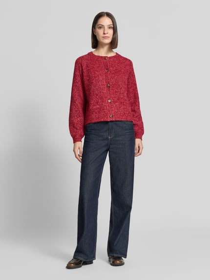 Frauenmodel trägt Relaxed Fit Strickjacke aus Woll-Mix Modell 'Nova' von LOLLYS LAUNDRY in Rot, grobe Textur, lange Ärmel, Ganzkörperansicht von vorne. Damen Strickjacke, durchgehende Knopfleiste, Rückenlänge 52 cm, Ärmellänge 47 cm.