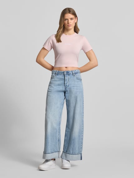 Vrouwenmodel draagt Cropped T-Shirt met Label-Stitching van Pegador in lichtroze, mix van katoen en elastaan, korte fit, ronde hals, ruglengte bij maat S 41 cm, voorkant geheel zichtbaar, Ganzkörperansicht von vorne.