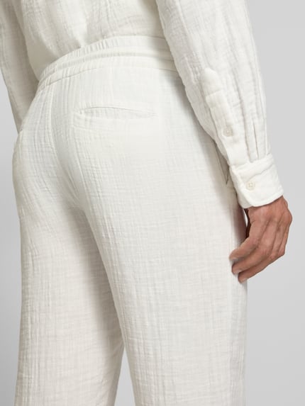 Männermodel trägt Straight Fit Sweatpants in Musselin-Optik von Lindbergh aus Reine Baumwolle in Weiß, Detailaufnahme Rückansicht.