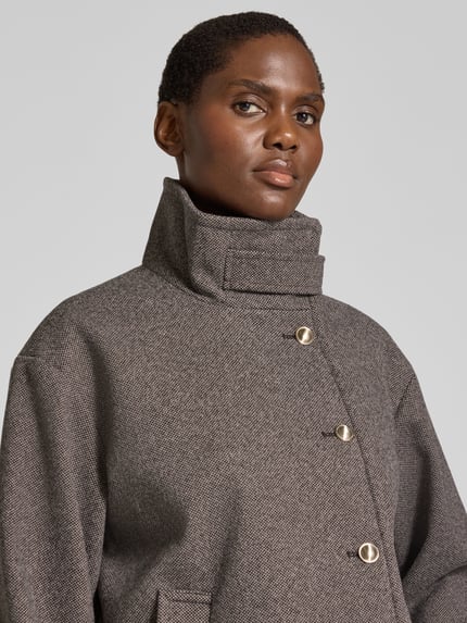 Frauenmodel trägt Bomberjacke mit hohem Stehkragen von VERO MODA in Grautönen mit grober Webstruktur, Nahaufnahme Oberkörper, Damen Teddy- / Webpelzjacke.