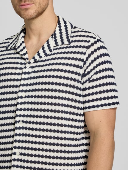 Männermodel trägt Relaxed Fit Poloshirt aus Baumwoll-Mix Modell 'DYLAN' von SELECTED HOMME, Optik:Allover-Muster, Nahaufnahme Oberkörper.