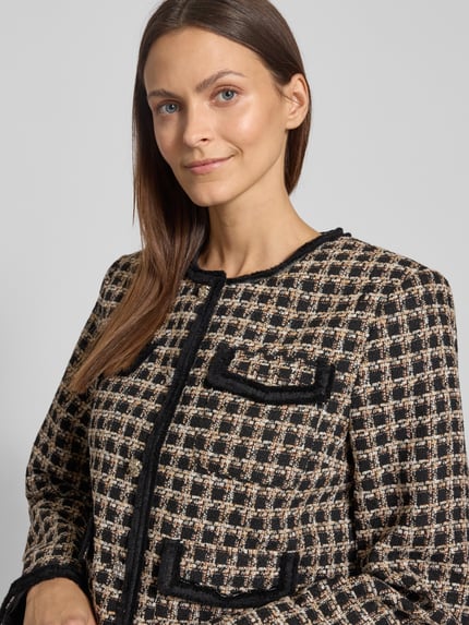 Kobieta modelka nosi Slim Fit Jacke in Bouclé-Optik Modell 'VISMO' od YAS w kolorach czerni i beżu, z patkami, okrągłym dekoltem, pełnym zapięciem na guziki, teksturowana tkanina, szerokość ramion 40 cm, długość rękawa 62 cm, szerokość klatki piersiowej 45 cm, długość 51 cm, półzbliżenie górnej części ciała.