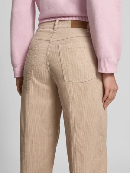 Männermodel trägt Straight Fit Cordhose mit Logo-Patch von BAUM & PFERDGARTEN, beżowy kolor, czysta bawełna, proste nogawki, kieszenie z przodu i z tyłu, guzik i zamek, szerokość w rozmiarze 36: 77 cm, długość wewnętrzna nogawki: 38 cm, widok całej sylwetki z tyłu