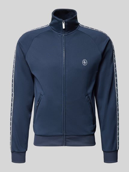 Produktfoto, Trainingsjacke mit aufgesetztem Band auf Raglanärmeln von REVIEW in Dunkelblau mit Logo, Stehkragen und Reißverschlusstaschen.