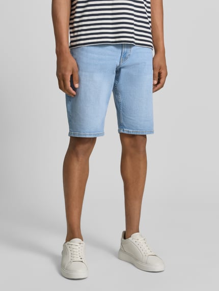 Männermodel trägt Regular Fit Jeans-Bermudas aus Baumwoll-Mix von s.Oliver RED LABEL in heller Denim-Optik mit Kontrastnähte, 5-Pocket-Design, Label-Patch, Nieten, Material: Baumwoll-Mix, Ganzkörperansicht von vorne.