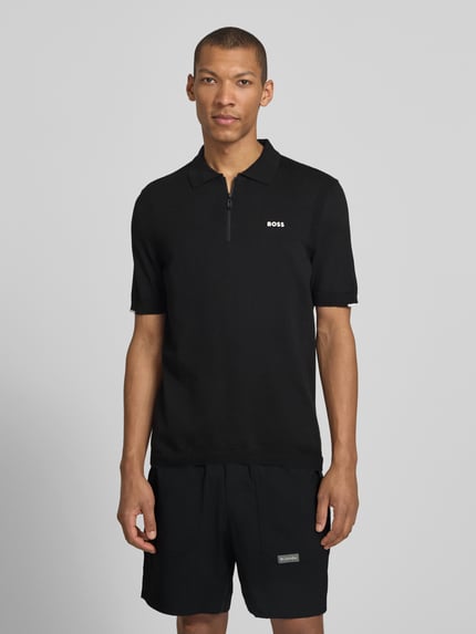 Männermodel trägt Regular Fit Poloshirt aus reiner Baumwolle Modell 'KN_EVER-X' von BOSS Green in Schwarz, Ganzkörperansicht von vorne.