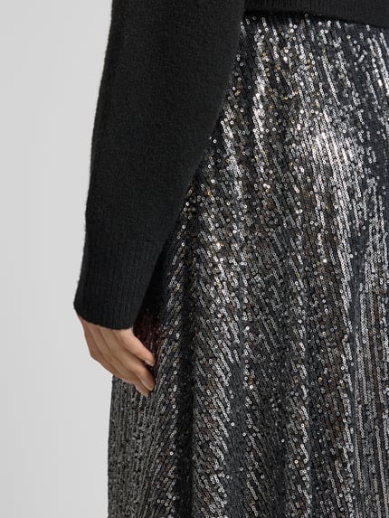 Frauenmodel trägt Maxirock mit Paillettenbesatz von Rich & Royal, Material-Mix mit Stretch-Anteil, lockerer Schnitt, Nahaufnahme Oberkörper.