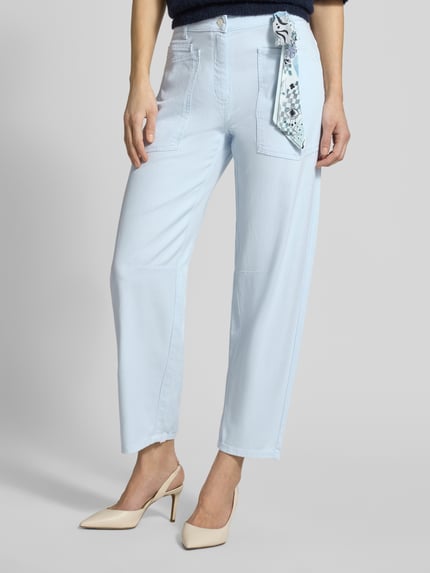 Vrouwenmodel draagt Relaxed Fit Jeans aus Lyocell-Mix van Cambio in lichtblauw met geknoopte doek, verkorte pasvorm, vooraanzicht, context: elastische lyocell-katoenmix, knoop- en ritssluiting, steek- en achterzakken, riemlussen.