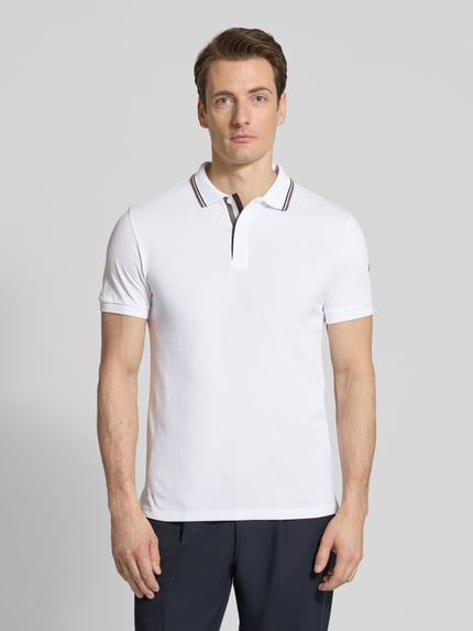 Männermodel trägt Slim Fit Poloshirt aus Baumwolle von Colmar Originals in Weiß mit Polokragen, Label-Details, Ganzkörperansicht von vorne. Rückenlänge bei Größe M: 66 cm.