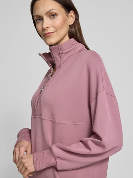 Frauenmodel trägt Sweatshirt mit Troyer-Kragen Modell 'molly' von VARLEY aus Viskose-Mix mit Stretch-Anteil, Relaxed-Fit, gerippte Ärmelabschlüsse, Nahaufnahme Oberkörper.