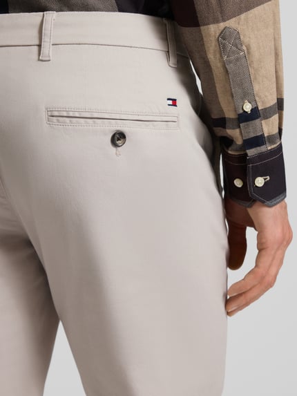 Männermodel draagt Regular Fit Chino uit katoenmix Model 'DENTON' van Tommy Hilfiger met all-over motief, detailopname van achterzijde.