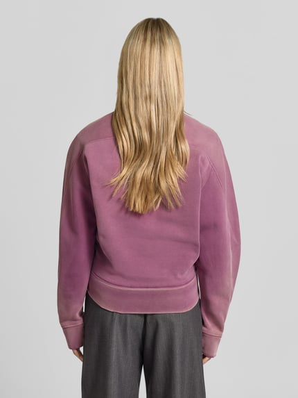 Vrouwenmodel draagt sweatshirt met Labelprint van Dsquared2 in paars, puur katoen, los model, ronde hals, ruglengte maat XS 61 cm, elastische boorden, Ganzkörperansicht Rückansicht