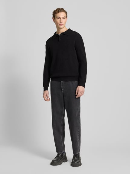 Männermodel trägt Poloshirt mit gerippten Abschlüssen von Forét, schwarz, Woll-Mix, Regular Fit, Ganzkörperansicht von vorne.